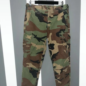 Cargobyxor camo Polo Ralph Lauren - Snygga cargobyxor från Polo Ralph Lauren i klassiskt camouflage-mönster. Byxorna har flera praktiska fickor på sidorna och är tillverkade i bomull. Perfekta för en streetwear-look eller när du vill sticka ut lite extra.Helt nya utan tags.  Passar en 34/36