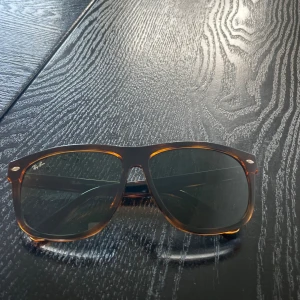 Ray-Ban boyfriend RB4147  solglasögon. - Snygga Ray-Ban boyfriend RB4147 solglasögon med brunmelerad båge och mörka glas. Klassisk  form och diskret logga på skalmen. 