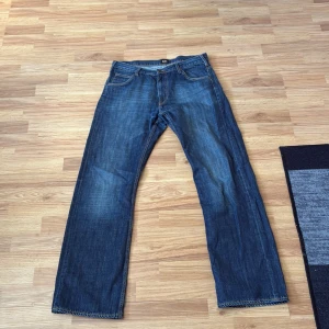 Blå jeans Lee Dillon W33 L34 - Säljer ett par klassiska blå jeans från Lee, modell Dillon. Jeansen har raka ben, normal passform och snygga kontrastsömmar. Tillverkade i slitstarkt denim med fem fickor och Lee-logga bak i midjan. Perfekta för dig som gillar tidlös stil. Skriv för fler frågor.kan gå ner i pris 