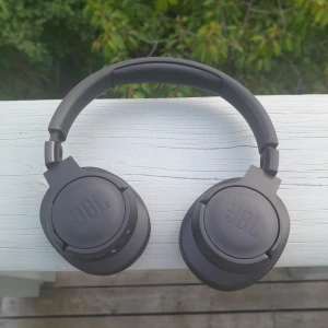 JBL Hörlurar i mycket bra skick - Bilderna visar ett par svarta JBL over-ear hörlurar. (Jbl tune bt720). Hörlurarna erbjuder mycket bra passform med vadderade kåpor som. Fungerar utmärkt för träning och under pass som innefattar mycket rörelse håller de sig stabil kvar på huvudet
