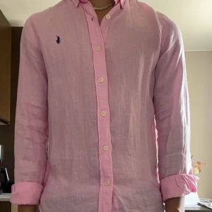 Rosa linneskjorta från Polo Ralph Lauren - Snygg rosa skjorta från Polo Ralph Lauren i slim fit-modell. Den är i mycket bra skick och kommer vara otroligt snygg nu i sommar. Nypris cirka 1600! Säljes nu för 599!😃✌️