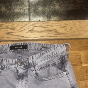 Replay Anbass ljusgrå jeans 31/34 - Säljer ett par ljusgrå Replay Anbass jeans med klassisk femficksdesign och snygga detaljer. Jeansen har raka ben och normal passform, tillverkade i mjukt bomullsmaterial. Perfekta för dig som gillar stilrena och bekväma jeans.