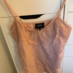 Rosa linnetopp med spets från Object - Supersöt ljusrosa linnetopp från Object med tunna axelband och vacker spetsdetalj upptill. Säljer då den endast ligger i garderoben, därav att den är skrynklig. Mycket bra skick🥰💕