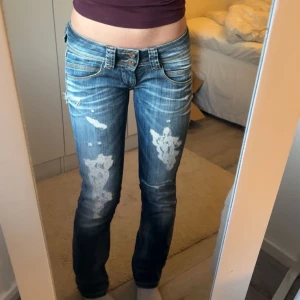 Blå jeans med slitningar - Säljer ett par blå jeans med coola slitningar. Jeansen har en låg midja och en straight passform. Passar mig som är storlek 34-36. Jag är 170 cm för referens. Kom privat för fler bilder!💞