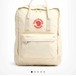 Beige Kånken ryggsäck från Fjällräven - Klassisk beige Kånken ryggsäck från Fjällräven med ikonisk röd logotyp framtill. Ryggsäcken har ett stort huvudfack, en dragkedjeförsedd ytterficka och två sidofickor. Praktiska handtag upptill och justerbara axelremmar. Perfekt för skola eller cityhäng. Färg light oak.