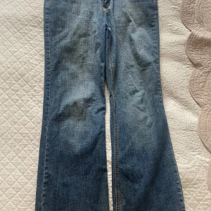 Bootcut jeans från Urban Star - Säljer ett par klassiska blå bootcut jeans från Urban Star med snygga broderade bakfickor. Jeansen har normal passform, är tillverkade i bomull och har kontrastsömmar. Perfekta för dig som gillar en tidlös jeanslook.