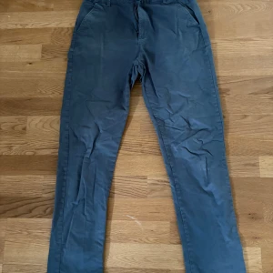 Blå chinos från M&S - Blå chinos från M&S med klassisk rak passform. Byxorna har fickor fram och bak.