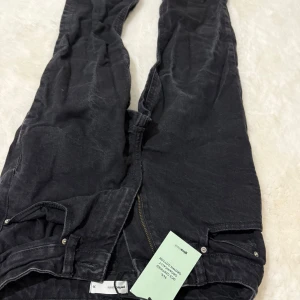 Svarta jeansbyxor från Piece of Jeans - Snygga svarta jeansbyxor från Piece of Jeans med klassisk femficksdesign och dragkedja. Jeansen är tillverkade i ekologisk bomull och har en mörk tvätt som ger en cool, avslappnad look. Perfekta för dig som gillar stilrena och bekväma jeans.