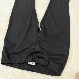 Svarta mjukisbyxor från Nelly - Svarta mjukisbyxor från Nelly med elastisk midja. Byxorna har en enkel och clean look, perfekta för chill dagar eller när du vill vara bekväm. Mjukt material som känns skönt mot huden.