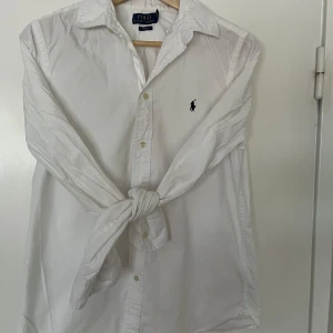 Vit skjorta från Polo Ralph Lauren - Säljer denna Klassiska vit skjortan från Polo Ralph Lauren med broderad logga på bröstet.  Tillverkad i bomull och har en slim fit-passform. Perfekt för en clean och stilren look och perfekt nu till sommaren! Den är i storlek XL i barn men passar precis som en vuxen S. Köpte den några månader sen för 1300 och den är i suverän skick!