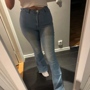 Ljusblå bootcut jeans med hög midja - Säljer ett par ljusblå jeans med bootcut och hög midja. Materialet är mjukt denim och passformen är slim upptill med utsvängda ben.