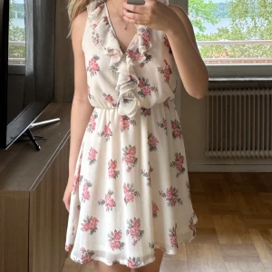 Blommig volangklänning från H&M Divided - Supersöt kort blommig klänning från H&M Divided i ljusbeige med rosa blommor. 