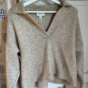 Stickad tröja från monki  - Beige stickad tröja från monki. Halsen är v-ringad med en liten krage. Använd ett fåtal gånger.