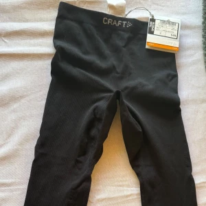 Svarta träningstights från Craft i S - Svarta, korta tights från Craft med ribbad struktur och bred resår i midjan. Tillverkade i en mix av polyamid, polyester och elastan för en stretchig och bekväm passform. Perfekta för träning eller chill dagar. Snygg och enkel design med diskret Craft-logga i midjan. Står för man men är mer unisex. Oanvända med prislapp kvar, 549kr