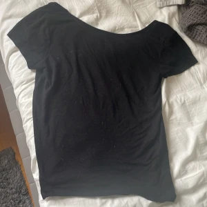 Svart t-shirt med öppen rygg  - En svart, enkel T-shirt från 157 med korta ärmar och snyggt öppen rygg. Gjord i mjuk bomull som känns skön mot huden. Perfekt för dig som gillar minimalistisk stil med en twist. Passar till allt och är lätt att matcha med andra plagg. Ganska bra skick, använd typ 5 gånger💞Säljer då den sitter inte tight på mig som jag vill att den ska göra!