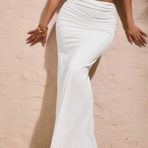 Vit kjol med rynkade detaljer - Supersnygg vit kjol med figurnära passform och rynkade detaljer vid höfterna. Säljer då den var väldigt lång på mig som är 155😊 Inga defekter och helt oanvänd.