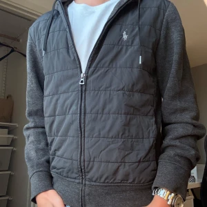 Polo Ralph Lauren Cardigan - Säljer denna sjukt snygga eftertraktade Polo Ralph Lauren för bara 879kr! Killen på bilden är 173 cm lång men tröjans ideal är ungefär 162-172. Tröjan kan användas året om till alla möjliga outfits. Liten skada på ryggen som knappast syns. Axelbredd: 44cm Längd: 60cm