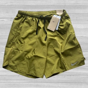 Nike Miler Shorts - Nike Dri-FIT shorts i olivgrönt med svart snörning i midjan. Lätta och snabbtorkande, perfekta för träning. Klassisk logga på benet och elastisk midja för skön passform. Snygg sportig look som funkar till gymmet eller löprundan.