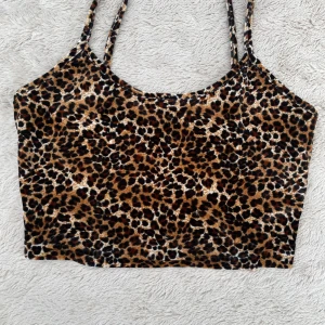 Leopardmönstrad croppad topp Shein - Säljer en croppad leopardmönstrad topp från Shein i storlek M. Toppen har tunna axelband och är figurnära med ett mjukt, stretchigt material. Perfekt för dig som vill sticka ut med ett djurmönster och gillar trendiga plagg.