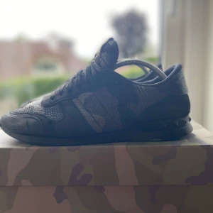 Valentino Rockrunners - Snygga Valentino Rockrunner sneakers i svart och grått camouflagemönster. Skorna har mesh och skinnpaneler, svarta snören och coola nitar på hälen. Perfekta för dig som vill sticka ut med exklusiva detaljer och streetkänsla. Ops box ingår inte
