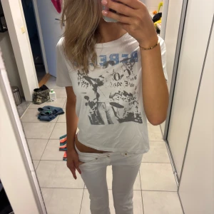 Vit t-shirt med tryck - Vit t-shirt med coolt svart och blått tryck framtill från Maje 