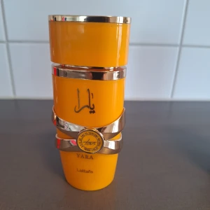 Yara Tous parfym från Lattafa - Yara Tous från Lattafa är en tropisk och söt parfym med inslag av vanilj, frukt och kokos. Flaskan är klargul med guldiga detaljer och har en modern, unik form. Perfekt för dig som gillar dofter med exotiska och pudriga toner. Ca 70 ml kvar