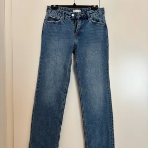 Blå raka jeans från Gina - Klassiska blå jeans från Gina tricot, modell Perfect Jeans med rak passform och normal midja. Jeansen har fem fickor, snygga kopparfärgade nitar och stängs med dragkedja och knapp. Perfekta till sneakers eller boots för en chill look. Aldrig använda