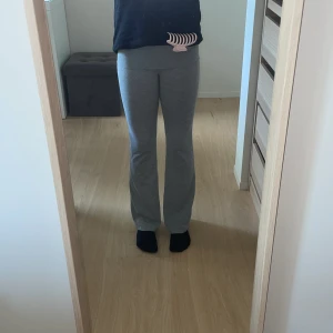 Gråa lågmidjade yogapants från Gina Tricot - Gråa yogapants från Gina Tricot i storlek 146/152. Byxorna har låg midja och bootcut-ben, vilket ger en snygg och avslappnad look. Tillverkade i mjukt bomullsmaterial som är skönt mot huden. Perfekta för chill dagar eller när du vill vara bekväm.