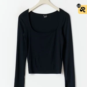 Svart långärmad topp med rund hals och slits i ärm ändarna från gina tricot - En svart långärmad topp med rundad halsringning och sltis i ärm ändarna. Tunt och mjukt material som sitter nära kroppen och passar perfekt till lager-på-lager. Enkel och stilren design utan mönster eller detaljer.