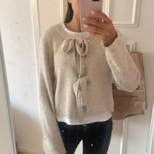 stickad kofta med knytband - Superfin beige stickad kofta med två stora knytband. I väldigt bra skick 