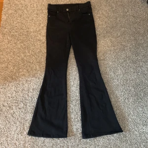 Svarta bootcut jeans från Dr. Demin Macy Black 101 - Snygga svarta jeans med bootcut-modell och klassisk femficksdesign. Byxorna har normal midja och är tillverkade i ett stretchigt jeanstyg som sitter skönt. Perfekta för dig som gillar en retroinspirerad look med utsvängda ben.