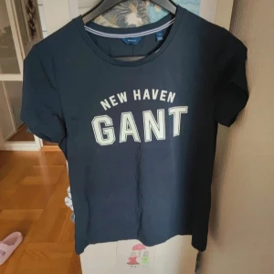 Mörkblå GANT t-shirt med tryck - Snygg mörkblå t-shirt från GANT med klassiskt 'NEW HAVEN GANT'-tryck på bröstet. T-shirten har rund halsringning och korta ärmar.Perfekt för en avslappnad och stilren look.