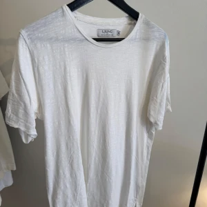 Vit t-shirt från Ljung - En stilren vit t-shirt från Ljung i klassisk modell med rund halsringning och korta ärmar. Tillverkad i mjuk bomull som känns skön mot huden. Perfekt för en clean och enkel look.