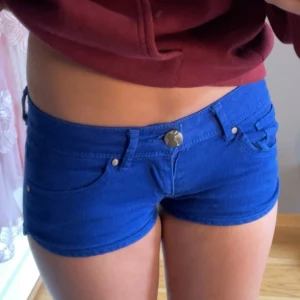 Blåa lågmidjade jeansshorts Tally Weijl - Snygga blåa lågmidjade jeansshorts från Tally Weijl. Modellen är tight och kort med klassiska fickor fram och bak, bälteshällor och dragkedja med knapp. Perfekta för varma sommardagar och en cool streetstil.