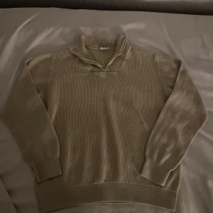Beige stickad half zip-tröja Kappahl - Säljer en beige stickad tröja från Kappahl med half zip-dragkedja och hög krage. Tröjan är ribbstickad och har långa ärmar samt breda muddar vid ärmslut och nederkant. Perfekt för lager-på-lager och chill stil.