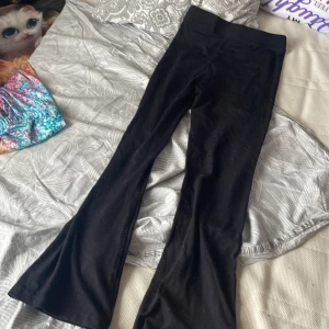 Svarta bootcut byxor från Reaction - Svarta byxor från Reaction i stretchigt material med bootcut-ben och bred resår i midjan. Snygg passform och klassisk look som funkar till många olika stilar. Perfekta för dig som gillar bekväma och trendiga byxor.