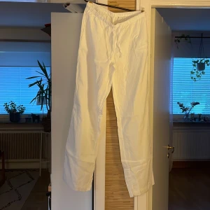 Vita linnebyxor med snörning - Säljer ett par vita linnebyxor med avslappnad passform och elastisk midja med snörning. Byxorna är raka i modellen och perfekta för en chill och stilren look. Lätta och luftiga, perfekta för varmare dagar.