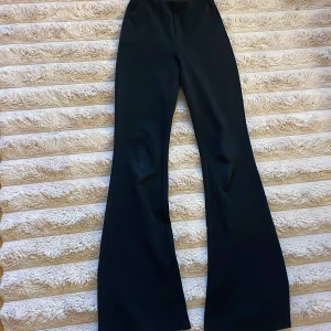Svarta bootcut byxor - Snygga svarta byxor med bootcut-modell och hög midja. De har en stilren look och vida ben som ger en trendig siluett. Perfekta att matcha med crop top eller oversized hoodie för en cool vibe.