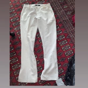 Vita bootcut kostymbyxor - Snygga vita kostymbyxor med bootcut-snitt och klassiska fickor fram. Byxorna har hällor för bälte och är perfekta för en clean och stilren look. Säljer nu dessa byxor för har blivit för stora på mig… byxorna är i storlek 40 men skulle säga passar även i storlek S också! Obs ( har ett litet hål där fram).