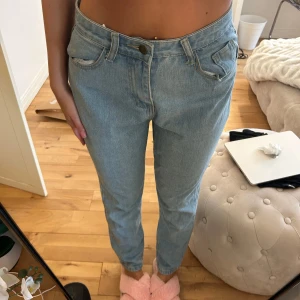 Ljusblå raka jeans - Säljer ett par ljusblå jeans med klassisk femficksdesign och raka ben. Jeansen har normalhög midja och stängs med knapp och dragkedja. Perfekta för en avslappnad och stilren look.