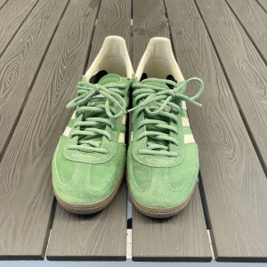 Adidas Handball Spezial gröna sneakers - Snygga Adidas Handball Spezial sneakers i ljusgrön mocka med klassiska vita ränder och detaljer. Skorna har bruna gummisulor, snörning och retrovibbar. Perfekta för dig som gillar streetstyle och vill sticka ut med en unik färg på fötterna. Pris kan diskuteras!