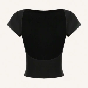 Svart croppad topp med öppen rygg - Säljer en svart croppad topp med korta ärmar och snyggt öppen rygg. Toppen har en tight passform och är perfekt för dig som gillar minimalistisk stil med en twist. Enkel att matcha med både jeans och kjol.