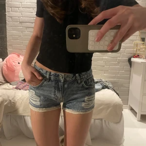 Blå jeansshorts med slitningar - Så söta blå jeansshorts med slitna detaljer och broderade kanter. Perfekta för en avslappnad stil. De har en klassisk femficksdesign och knappgylf. Passar perfekt till sommaren!!!🩷🩷☀️☀️nypris 600kr!