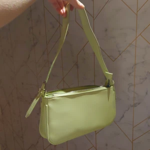Ljusgrön axelväska från Gina Tricot - Snygg ljusgrön axelväska från Gina Tricot med dragkedja upptill. Perfekt för att ge en färgklick till din outfit. Enkel och stilren design som passar till många tillfällen.