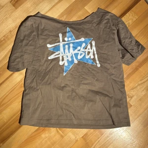 Stüssy t-shirt - Säljer denna jättefina off shoulder t-shirt! Den är köpt i Spanien och alltså är inte äkta men fortfarande jättefin och i bra kvalité! Den är klippt längst kragen. Hör av er om ni har frågor!🫶