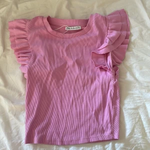 Rosa ribbad topp från Zara - Söt rosa ribbad topp från Zara med volangdetaljer på ärmarna. Perfekt för en somrig look med sin fräscha färg och luftiga design. Säljer då den inte används och nästan aldrig har används skriv för frågor eller bilder 💖