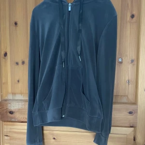 Grå hoodie med dragkedja - Säljer en stilren grå hoodie med dragkedja och huva. Den har långa ärmar och praktiska fickor framtill. Perfekt för en avslappnad look.