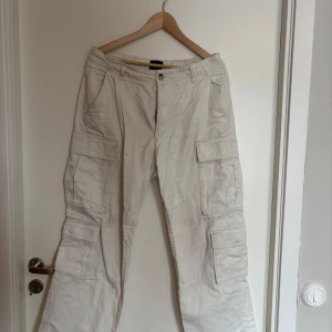 Beige cargobyxor med relaxed fit - Säljer ett par beige cargobyxor med relaxed fit. Byxorna har flera praktiska fickor på sidorna och bak. Perfekta för en avslappnad stil.