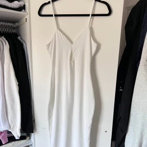 Vit klänning - Snygg vit klänning med smala axelband och en elegant v-ringning. Perfekt för sommarens alla tillfällen. Klänningen har en figurnära passform som framhäver silhuetten. Fin öppen detalj mellan brösten. Aldrig använd 🤍 Önskar du veta exakta mått? Tveka inte att höra av dig!