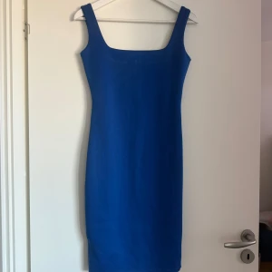 Blå klänning från Missguided - Snygg blå klänning från Missguided med en tight passform. Klänningen har breda axelband och en dragkedja i ryggen för enkel påklädning. Perfekt för en stilren look.